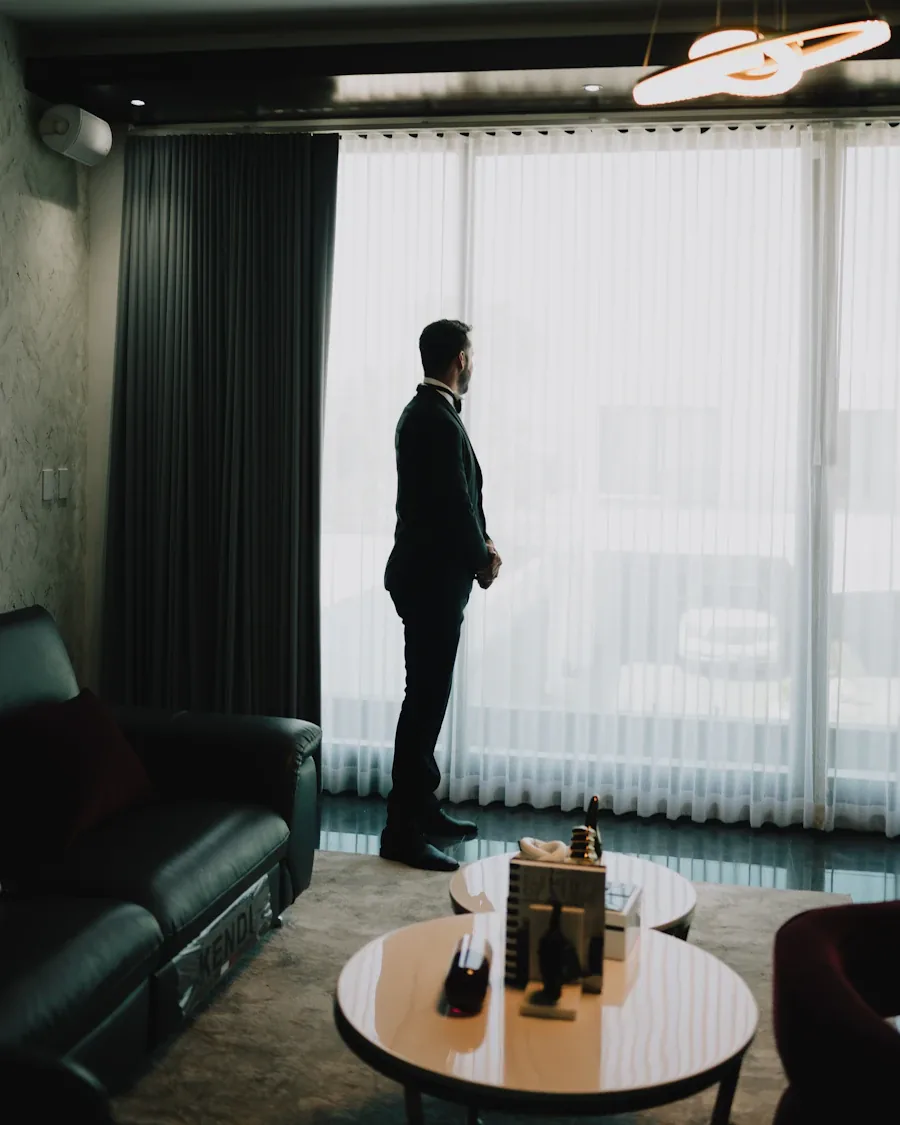 Man in an open-collar shirt and blazer in a hotel suite overlooking the city